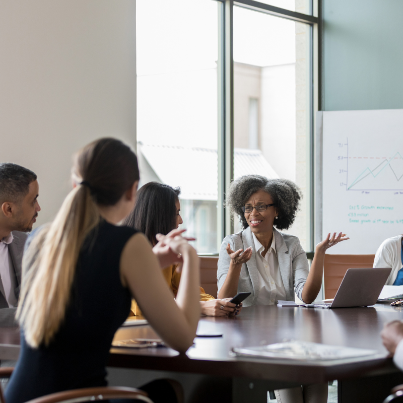 Employees gathered around a work table for year-end board meeting